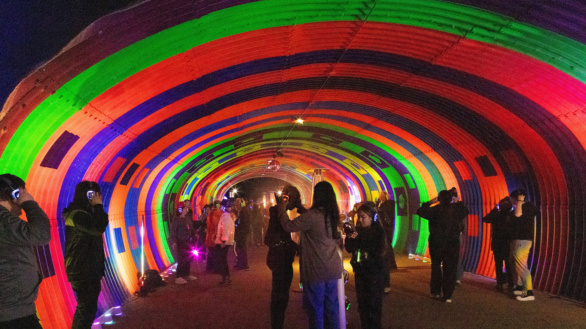 People participating in silent disco in brightly colored tunnel