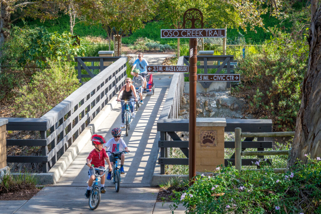 Family riding bikes across bridge on creek trail