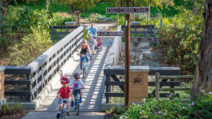 Family riding bikes across bridge on creek bike trail